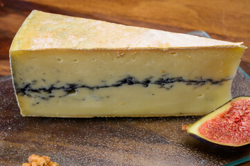 French semi-soft cow milk cheese morbier from Franche-Comte region with thin black layer and strong aroma close up