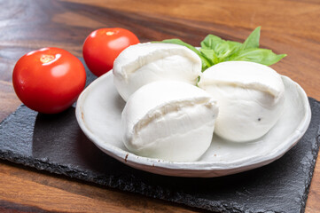 White balls of Italian soft cheese Mozzarella di Bufala Campana served with fresh green basil and red tomato