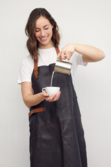 Professional barista woman serving a cup of coffee and pouring milk. Isolated on white background.