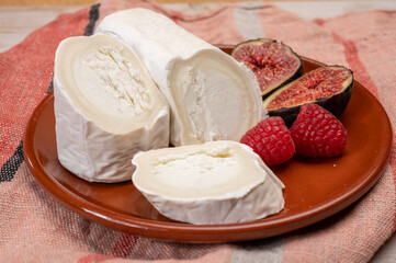 French organic matured white goat cheese with white rind close up served with fresh raspberries and figs