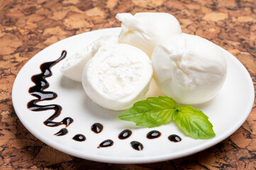 Eating of fresh handmade soft Italian cheese from Puglia, white balls of burrata or burratina cheese made from mozzarella and cream filling served with balsamico cream