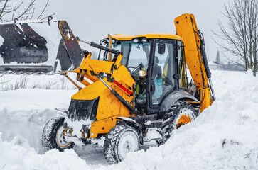 Yellow tractor cleans up snow from road. Cleaning and cleaning of roads in city from snow in winter