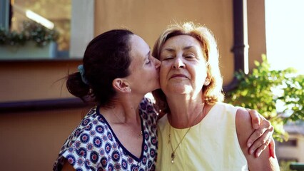 Joyful adult daughter kissing older mother in cheek. Family bonding loving relationship. Two different generations of women