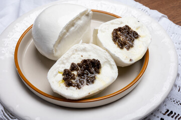White balls of Italian soft cheese Mozzarella di Bufala Campana stuffed with black truffles mushrooms