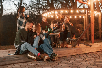 Lovely couple. Group of people is spending time together on the backyard at evening time