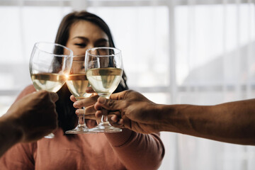 Cheers! Young happy friends are toasting at the  party at home. All wearing casual clothes and having fun together