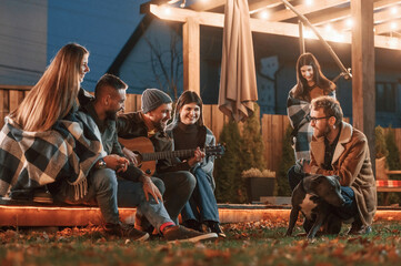 Cute dog. Group of people is spending time together on the backyard at evening time