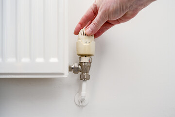 close up of plumber person turning up a thermostatically controlled radiator valve.