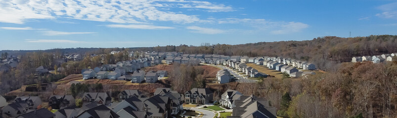 Panorama aerial upscale houses with side garage entry new development subdivision sprawl leads to horizontal line under rare cloud formation suburbs Atlanta, Georgia, USA - obrazy, fototapety, plakaty