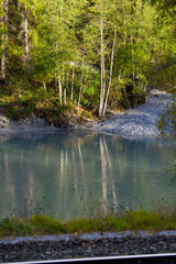 Reflections of trees in Rhine River at gorge of Anterior Rhine Valley on a sunny autumn day. Photo taken September 26th, 2022, Versam, Switzerland.
