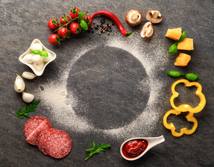 Frame of set ingredients for cooking italian pizza on a dark stone background, top view