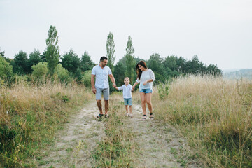 Obraz premium Happy young family father, mother and little son having fun outdoors, playing together in park