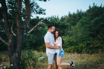 Fototapeta na wymiar Happy in love romantic young cheerful couple man and woman walk together among the summer forest