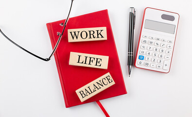 WORK LIFE BALANCE text on a wooden block on red notebook