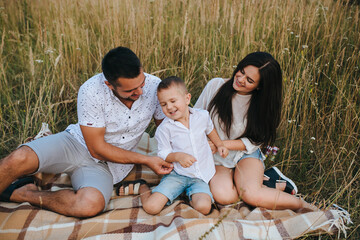 Happy young family father, mother and little son having fun outdoors, playing together in park