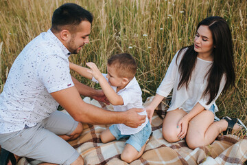 Happy young family father, mother and little son having fun outdoors, playing together in park