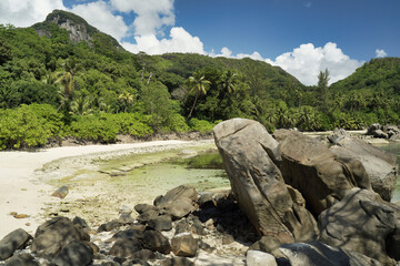 Rock boulder beach, white sandy beach and green vegetation