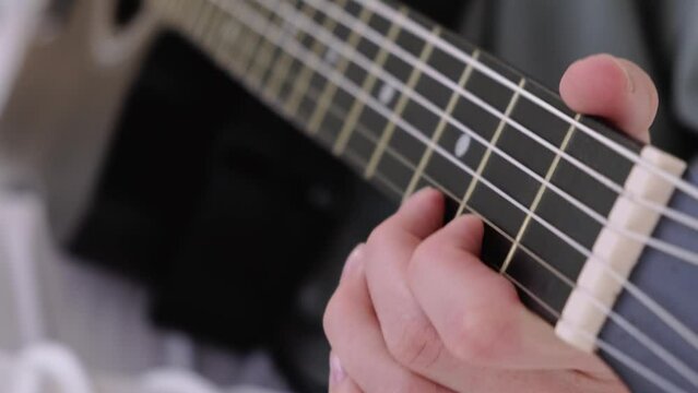 hands close up, girl pinches chords with her fingers, playing acoustic classic guitar, singing song and relaxing at home