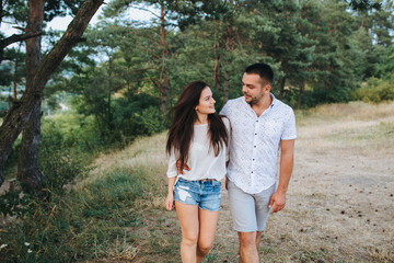 Happy in love romantic young cheerful couple man and woman walk together among the summer forest