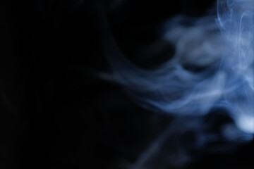 Graceful swirls of blue incense smoke isolated from black background. Close-up of vapor. Soft focus...