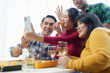 Friends at birthday party clinking glasses with champagne and pizza, enjoying Christmas vacation, pizza on the table. Holiday Party event.