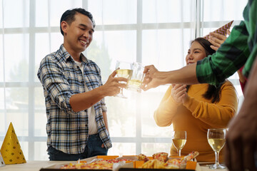 Friends at birthday party clinking glasses with champagne and pizza, enjoying Christmas vacation, pizza on the table. Holiday Party event.