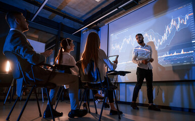 Trading teaching. Male leader talking to employees, showing the plan on the projector in office of...