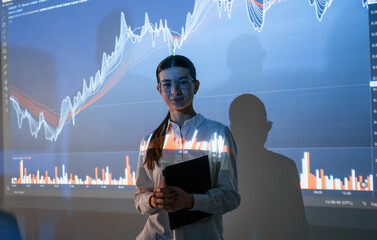Woman is standing near projector with the finance graphs