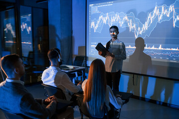 Exchange company. Female leader talking to employees, showing the plan on the projector in office...