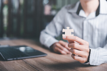 Businessman holding a puzzle piece to find a business solution,Connecting success and problem solution, from creativity,and strategic planning to develop the organization into the future