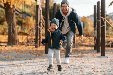 Fototapeta premium Playing, having fun together. Father and young son is together outdoors at daytime