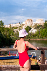 Fototapeta premium A girl in a red swimsuit and a panama hat on a sandy beach at the former White Well quarry near the city of Voronezh, summer landscape