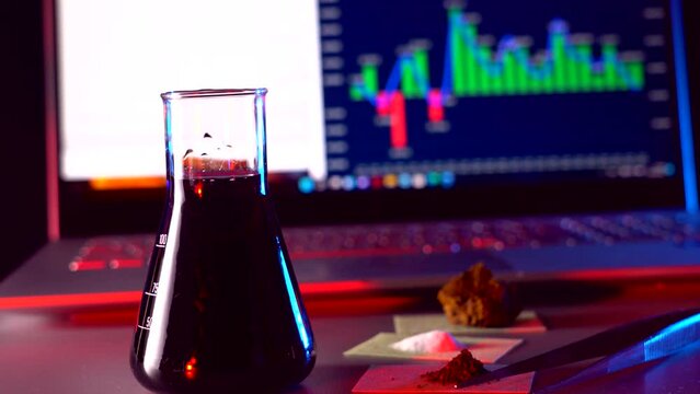 Scientific research in biology and chemistry. The experiment with the flask and the reaction with the clarification of the liquid. Desktop with a laptop with scientific charts.