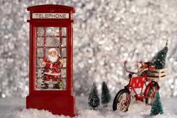 Santa in the telephone box, with Santa's bicycle in the silver wood. Christmas decoration