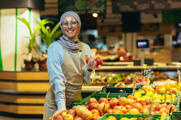 Portrait of saleswoman in supermarket, happy woman in hijab smiling and looking at camera, seller...