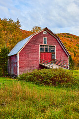 Obraz premium Up close to beautiful red barn aging in fields with colorful fall mountains behind