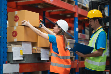 Asian warehouse workers lifting boxes on the shelf checking goods box shelf stock in the warehouse factory store, worker barcode scaner check stock. Warehouse Logistic concept.
