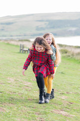 Naklejka na ściany i meble Two little girls sisters playing outdoor near Cuckmere beach located between Eastbourne and Seaford, East Sussex, British south coast, selective focus