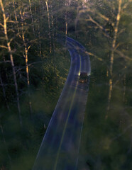 Vintage pickup truck with illuminated tail lights drives on road in a lush forest. High angle view. 3D render.
