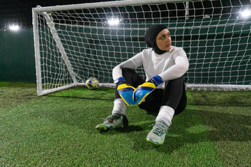 Female goal keeper sitting on ground