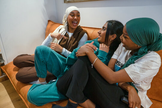 Smiling women wearing hijabs talking at home