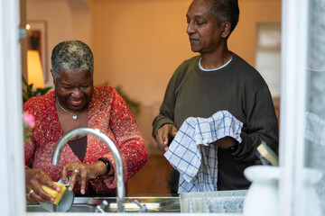 Senior couple washing dishes at home