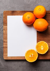 white paper and oranges on wood on dark marble background