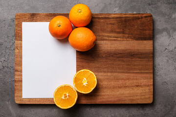 white paper and oranges on wood on dark marble background