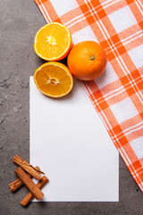 oranges with white checkered cloth sheet and cinnamon on dark marble background