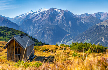 Fototapeta na wymiar Vordere, Mittlere and Hintere Grinberspitze massive viewed from Gerlossteinwand. Alpine mountains on a beautiful sunny day of autumn. Hiking in Austrian Alps. Old wooden hut falling apart.