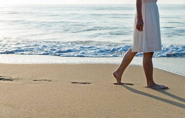 Woman legs walking on beach.
