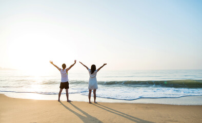 Young couple embracing enjoying ocean on beach.