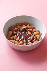 dark chocolate cream pouring on almond nut on white 