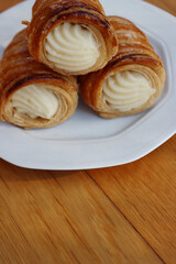 Italian traditional Cannoli filled with vanilla Custard cream on plate on wooden table
